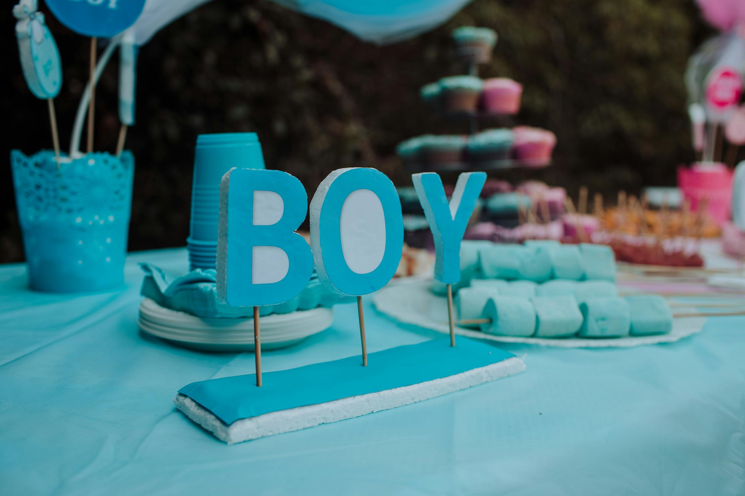 Blue-themed baby gender reveal party with decorations, indicating a boy. Festive atmosphere with sweets and decor.