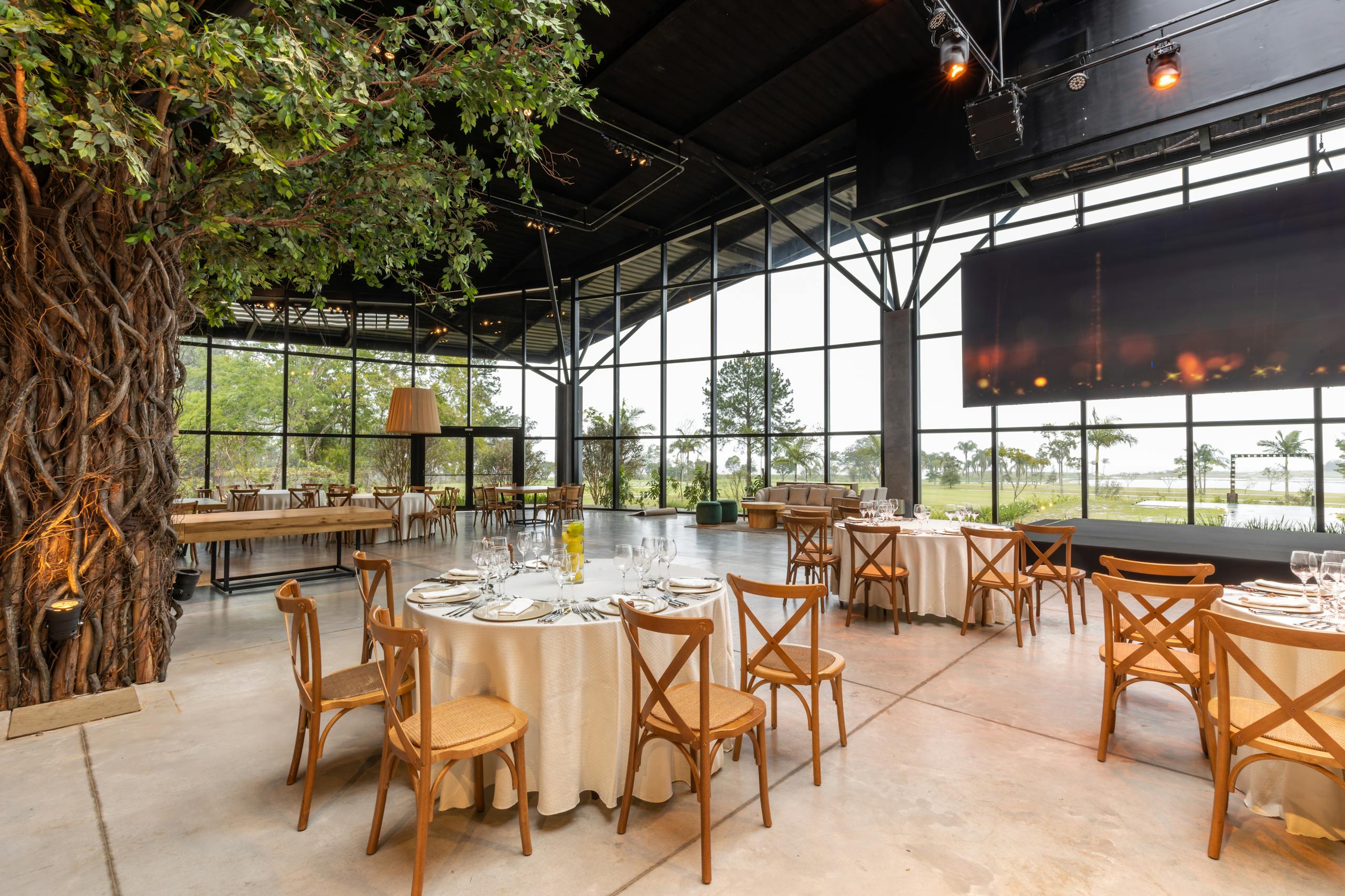 Spacious restaurant interior featuring modern decor, a large screen, and beautifully arranged tables for an elegant event.
